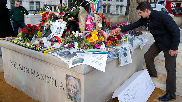 מניחים פרחים על פסלו של מנדלה בלונדון (צילום: AP)
