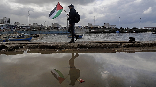 Man holds Palestinian flag at Gaza port. (Photo: Associated Press)