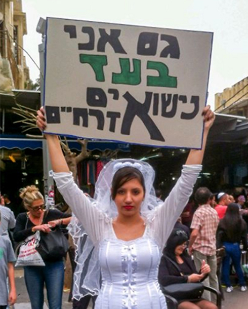 Woman dressed as bride holds sign reading 'I'm also in favor of civil marriage'
