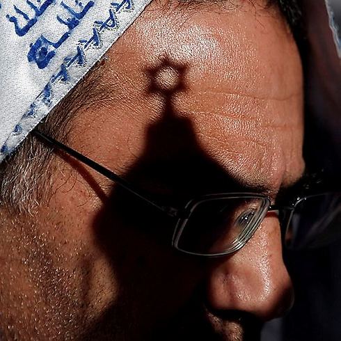 A star of David casts a shadow across a worshipper's face (Photo: AFP)