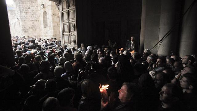 A Christian pilgrim holds up a candle as others gather at the church of the Holy Sepulcher (Photo: AP)