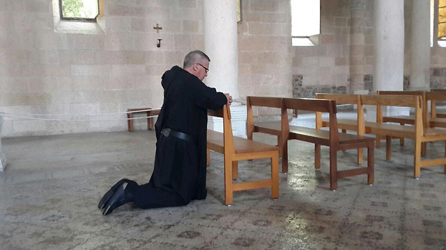 Father Gregory Collins praying at the church the morning after the fire (Photo: Ahiya Raved)