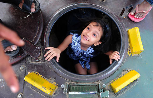 An Indian girl looks up from an army tank during  the 'Know Your Army' exhibition. (Photo: AFP)