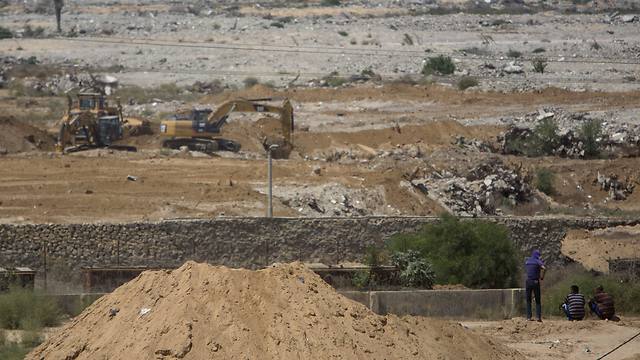 Palestinians sit and watch bulldozers and diggers work at the Egyptian side of the border with Gaza Strip (Photo: AP)