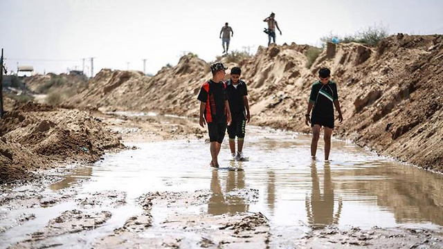 Egyptian children walk on the remains of a flooded tunnel