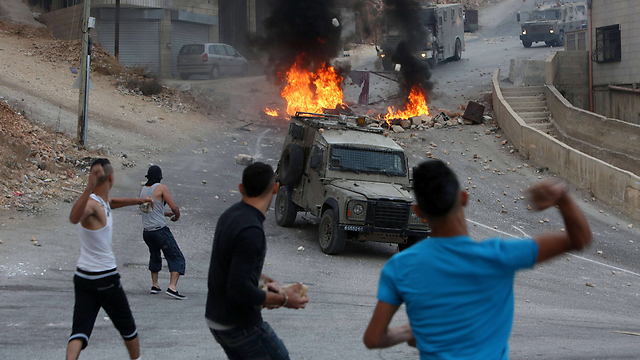 Palestinians throw rocks at military vehicles in Nablus. (Photo: AFP)