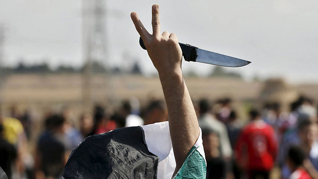 A rioter brandishing a knife throws up a victory sign (Photo: Reuters)