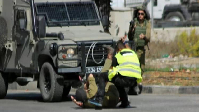 The Palestinian attacker stabbing a soldier on the ground.