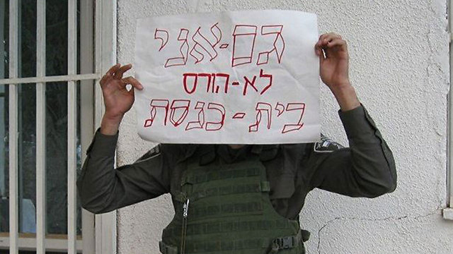 A Border Police officer holds a sign saying "I too won't demolish a synagogue." (Photo: Facebook)