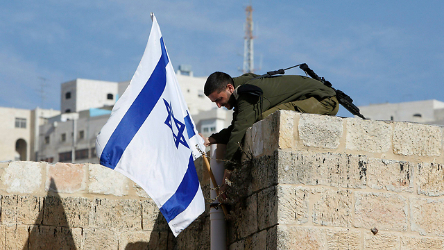 An IDF soldier removing an Israeli flag from a house in Hebron after settlers who had just moved in were evicted (Photo: Reuters)
