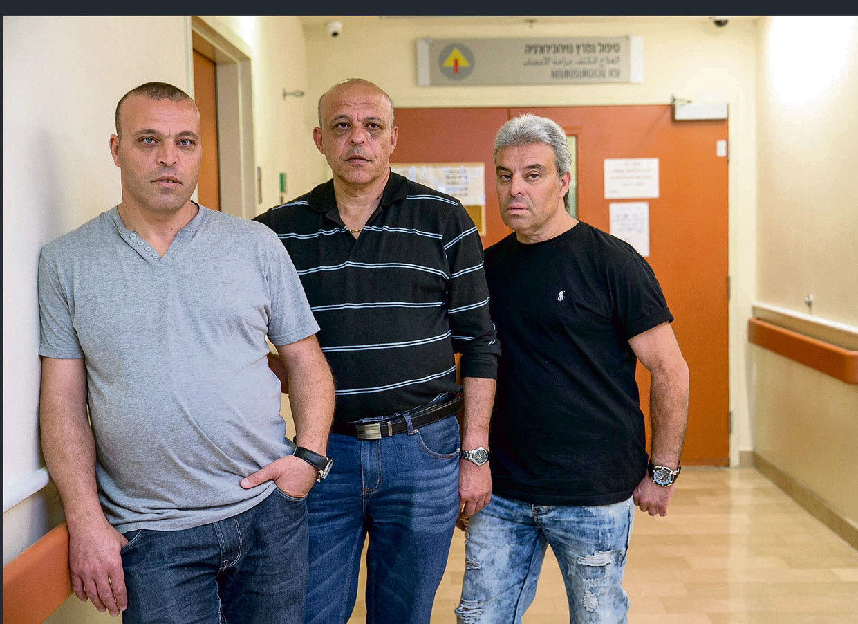 Brothers Yuval, Yuval, and Rami Cohen outside the room in which Tzika lies (Photo: Ohad Zwigenberg)