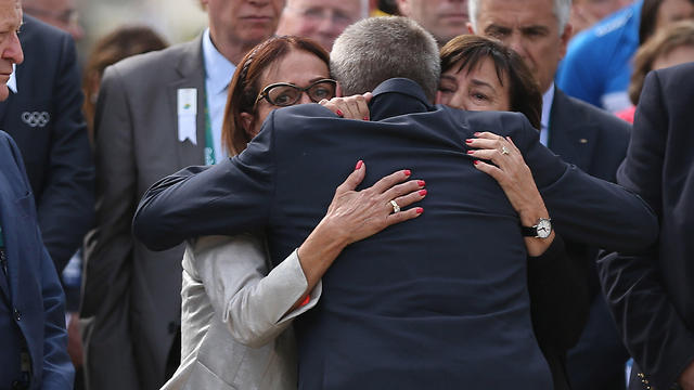 IOC President Thomas Bach, back to camera, embraces Ilana Romano, right, and Ankie Spitzer (Photo: AP)