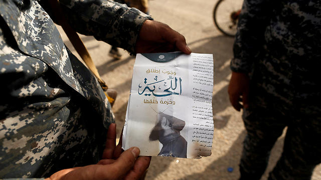 An Iraqi soldier shows a pamphlet which reads 'Wearing beards is compulsory, shaving is prohibited' along a street of the town of al-Shura, which was recaptured from ISIS on Saturday, south of Mosul (Photo: Reuters)