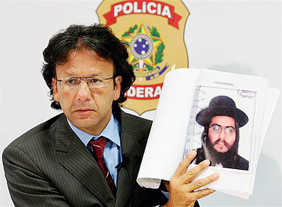 נתפס בברזיל. השוטר המקומי עם כרזות "מבוקש" (צילום: AP) (צילום: AP)