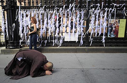 נזיר מתפלל ליד הסרטים שנתלו ליד הגראונד זירו, לזכר קורבנות מתקפת הטרור (צילום: AFP) (צילום: AFP)