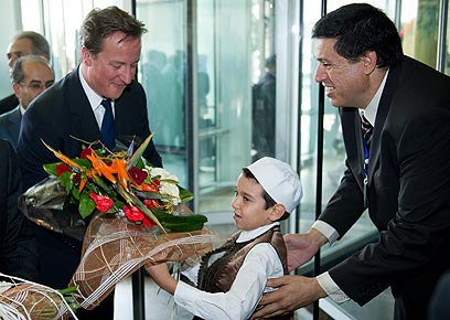 קמרון מקבל פרחים מידי ילד לובי. הבטיח לסייע לתלמיד פצוע (צילום: AFP) (צילום: AFP)