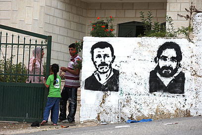 פקרי ונאיל ברגותי על הקיר ברמאללה. ותיקי האסירים יצאו לחופשי (צילום: AFP) (צילום: AFP)