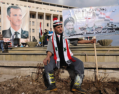 אסד ייפול? תושב דמשק עם תמונת מנהיג חיזבאללה נסראללה (צילום: רויטרס) (צילום: רויטרס)
