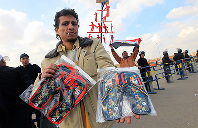 רוכל מחוץ לאולם המשפט מוכר כפכפים שעליהם דמותו של מובארק (צילום: AFP) (צילום: AFP)