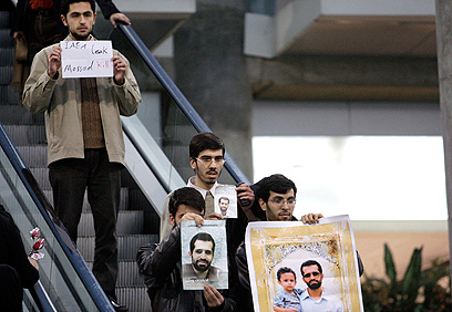 המפגינים עם תמונותיו של אחמדי-רושאן (צילום: AP) (צילום: AP)