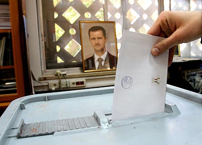 השגחה נשיאותית. מצביע בדמשק על רקע תמונת אסד (צילום: AFP) (צילום: AFP)