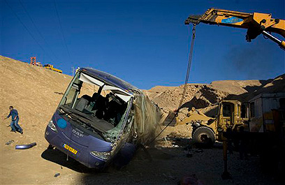 Workers remove the destroyed bus (Photo: AP)
