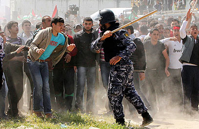 איש ביטחון של חמאס בעזה מול מפגינים ביום האדמה (צילום: רויטרס) (צילום: רויטרס)