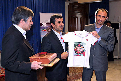 אחמדינג'אד מקבל חולצה עם תמונת המדען האחרון שחוסל, מוסטפא אחמדי רושן (צילום: AFP PHOTO / HO/ IRANIAN PRESIDENCY WEBSITE) (צילום: AFP PHOTO / HO/ IRANIAN PRESIDENCY WEBSITE)