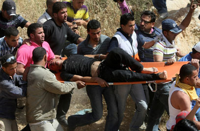 הפלסטיני הפצוע מפונה מהמקום. היורה לא נעצר (צילום: AFP) (צילום: AFP)