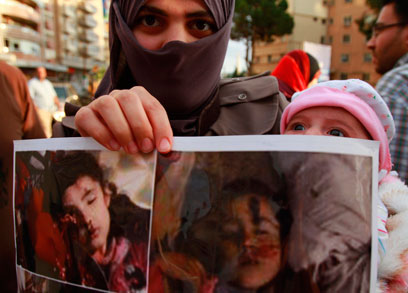 מפגינים בלבנון עם תמונות ההרוגים (צילום: רויטרס) (צילום: רויטרס)