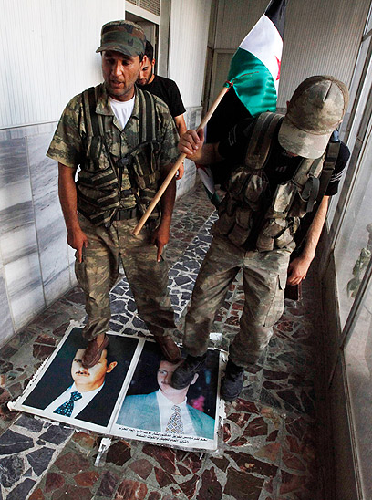 מורדים סורים דורכים על תמונות אסד (צילום: רויטרס) (צילום: רויטרס)