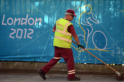 מצחצחים את הרחובות כשברקע אחת מהפרסומות הבודדות למשחקים (צילום: AFP) (צילום: AFP)