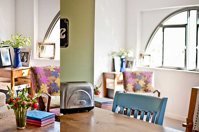 העמוד הרחב המפריד בין המטבח לסלון נצבע בגוון ירוק, והפך להיות חלק מדלפק האוכל. ברקע חלון הקשת (צילום: סיון אסקיו) (צילום: סיון אסקיו)