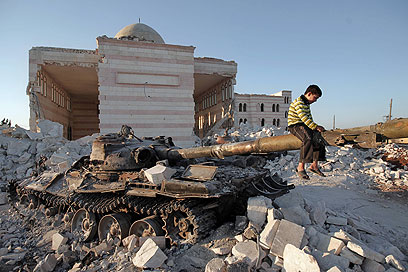 התערבות צבאית לא נראית באופק. ילד סורי משחק על טנק הרוס בעזאז (צילום: AFP) (צילום: AFP)