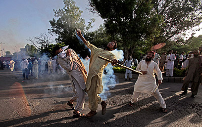מפגין בפקיסטן זורק מכל גז מדמיע לעבר השוטרים (צילום: AP) (צילום: AP)