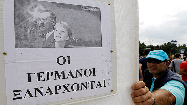אויבת הציבור ביוון. מרקל לצד היטלר על גבי כרזה באתונה (צילום: AP) (צילום: AP)