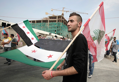 מפגין נושא את דגלי לבנון והמורדים הסורים (צילום: AP) (צילום: AP)