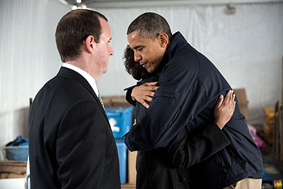 אובמה מחבק את גלנדה וג'ון מור ששני בניהם הקטנים נסחפו בשיטפון שיצרה הסופה ונספו ()