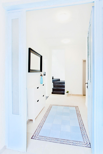 דלת הכניסה לבית נצבעה בתכלת וכך גם הרצפה שרוצפה ב"שטיח אריחים" בצבע תכלת עם מסגרת מעוצבת (צילום: שרון קנה) (צילום: שרון קנה)