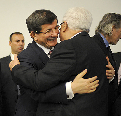 נשיא הרשות מתחבק עם שר החוץ הטורקי דבוטאולו בניו-יורק (צילום: AFP) (צילום: AFP)