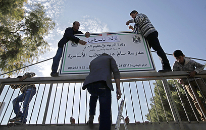 מחליפים שלט לבית ספר עם הכותרת "מדינת פלסטין" (צילום: AFP) (צילום: AFP)