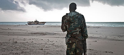 שודד ים בחוף סומליה מביט על ספינה שנחטפה (צילום: AP) (צילום: AP)