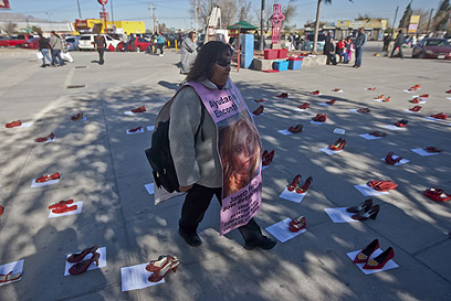 מפגינה בסיודד חוארס. על הקרקע: נעליים אדומות שמסמלות את הנשים הנעדרות (צילום: AFP) (צילום: AFP)