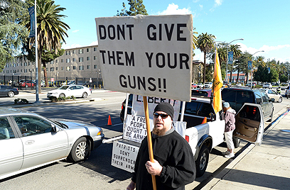 מפגין נגד האיסוף. "אל תתנו להם את הרובים שלכם" (צילום: AFP) (צילום: AFP)