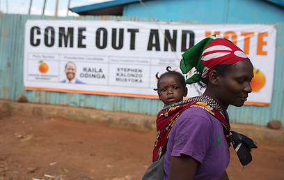 תושבת שכונת קיברה בניירובי ליד כרזת בחירות (צילום: רויטרס) (צילום: רויטרס)