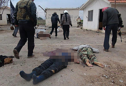 מורדים חולפים על פי גופות חיילים סורים בבסיס שכבשו (צילום: AP) (צילום: AP)