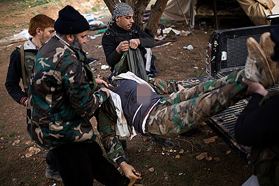 מורדים מפנים גופת חייל לאחר שכבשו את האקדמיה הצבאית בתל-שער (צילום: AP) (צילום: AP)