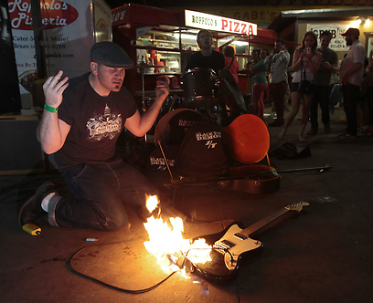 חבר להקת "Black top Demon" מבעיר את הגיטרה בהופעה ברחובות העיר (צילם: EPA) (צילם: EPA)