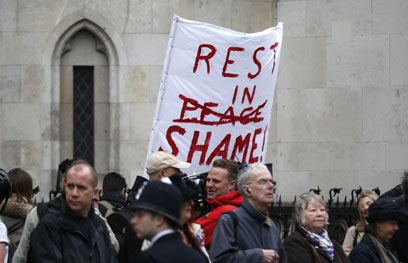 "נוחי על משכבך בבושה". שלט מחאה במסע ההלוויה (צילום: AFP) (צילום: AFP)
