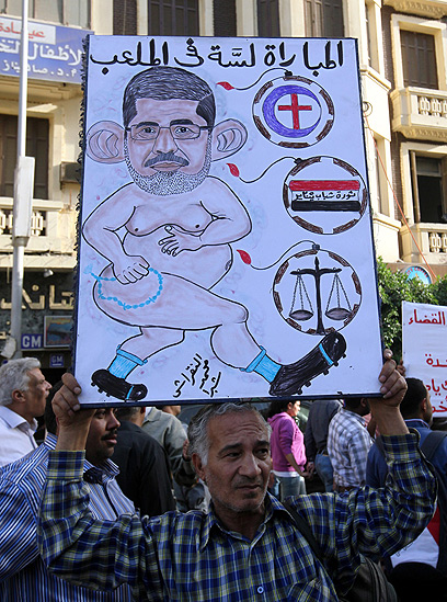 הפגנה נגד הנשיא מול בית המשפט העליון בקהיר. קריקטורה בגנות מורסי (צילום: EPA) (צילום: EPA)